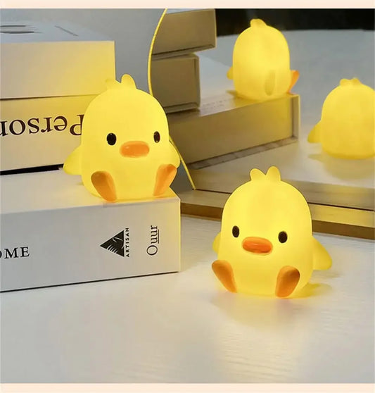 Yellow duck-shaped night lights on a surface with books in the background